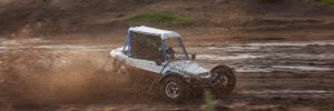 a small sports buggy racing vehicle with a child driving on a rally competition track during weekend training on a warm summer day.