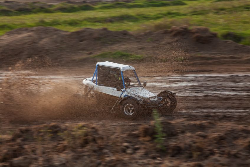 a small sports buggy racing vehicle with a child driving on a rally competition track during weekend training on a warm summer day.